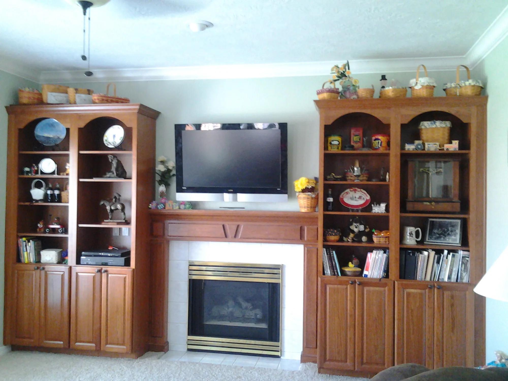 Stained mantel shelf over a carved frieze panel with pilasters, built into a full wall of stained bookcase towers