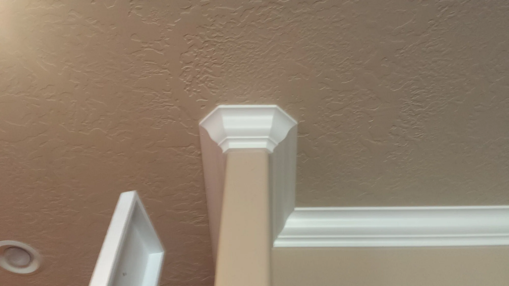 Mitered white crown capital on the top of a painted box column with the matching cornice band running along the wall